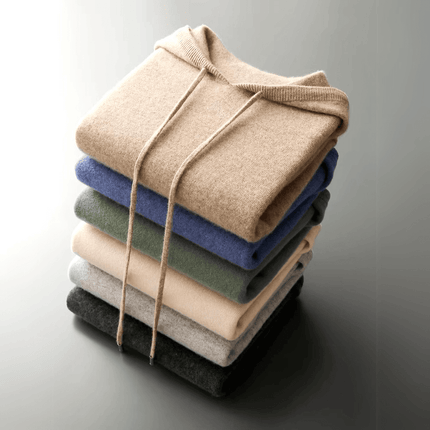 Stack of folded Monaco Hoodie in warm, soft merino wool showcasing various colours, ideal for men's winter sweater collections.